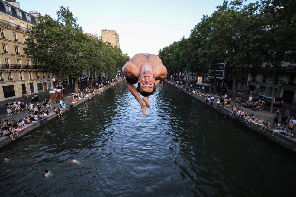 Un adolescent plonge depuis un pont dans le canal Saint-Martin alors que la canicule s'abbat sur la France à Paris, le 25 juin 2026.