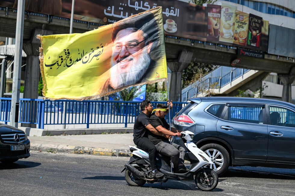 Des  partisans du Hezbollah brandissent un drapeau à l'effigie du défunt leader Hassan Nasrallah, le 26 juin 2026 dans la banlieue sud de Beyrouth, à l'occasion de la commémoration de l'Achoura, journée de deuil pour la mort de Hussein, figure clé de l'islam chiite.