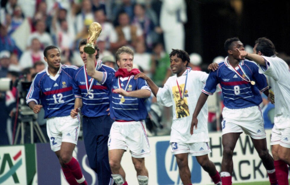 Les joueurs de l'équipe de France célèbrent leur victoire contre le Brésil après la finale de la Coupe du monde de football, le 12 juillet 1998, au Stade de France à Saint-Denis, au nord de Paris. De gauche à droite : Thierry Henry, Laurent Blanc, le capitaine Didier Deschamps brandissant le trophée, Bernard Diomède, Marcel Desailly et Alain Boghossian.